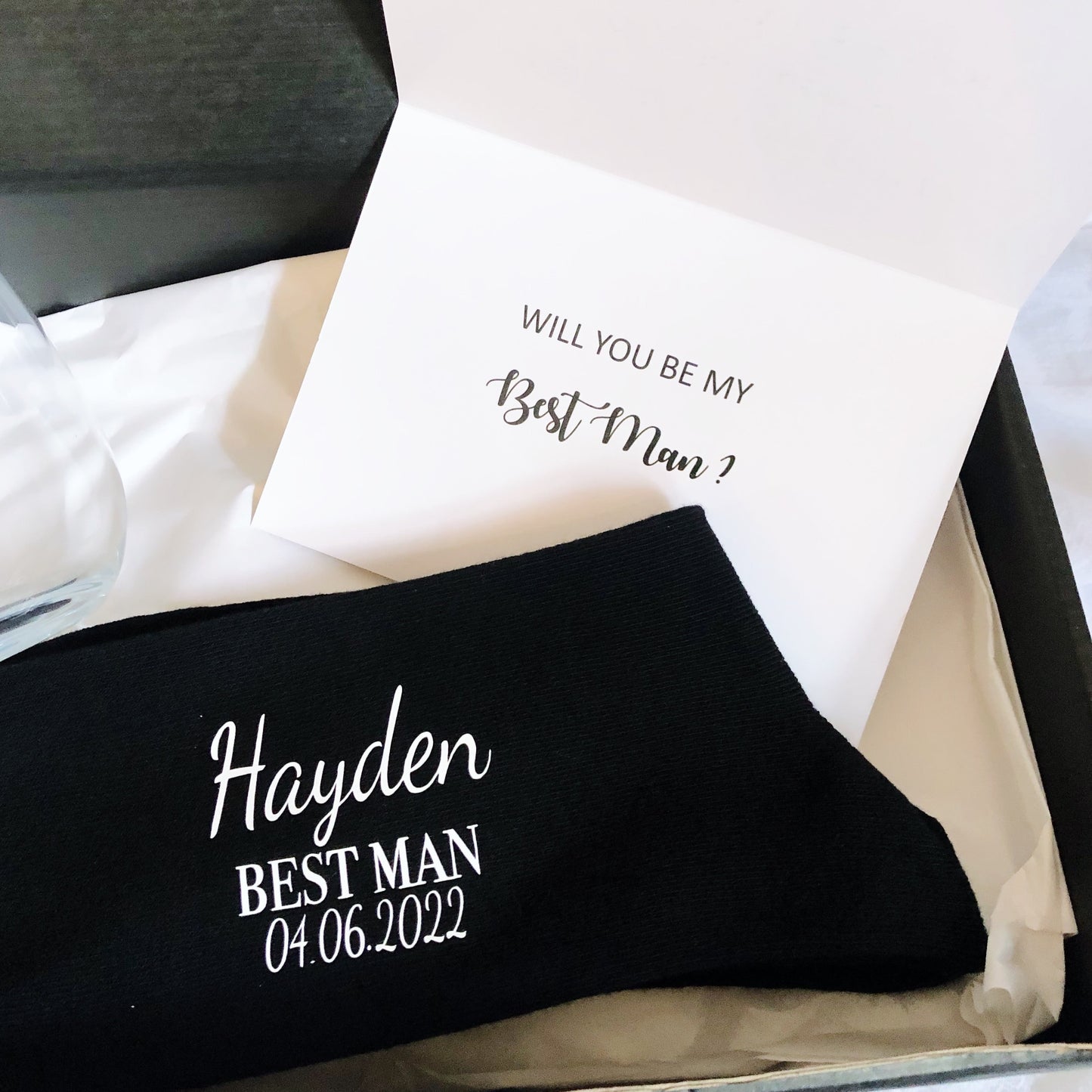 Find the perfect groomsman gift box, featuring personalized items such as glasses, socks, and a card, all elegantly packaged to make your wedding party feel special.