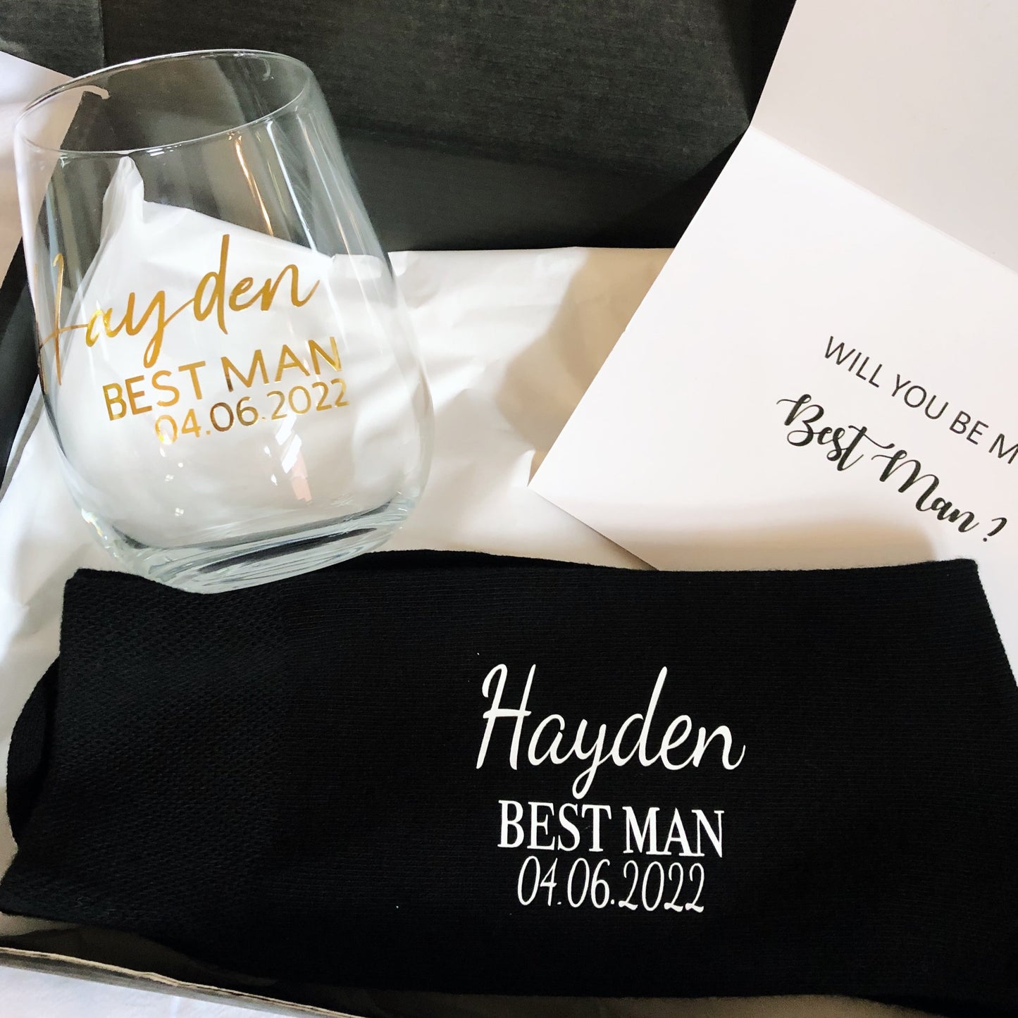 Find the perfect groomsman gift box, featuring personalized items such as glasses, socks, and a card, all elegantly packaged to make your wedding party feel special.